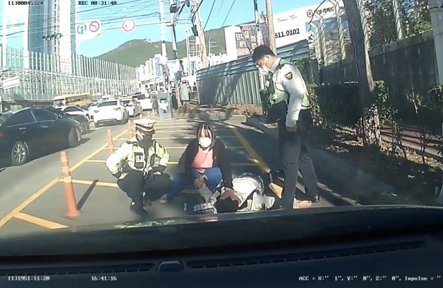 19일 오전 부산 남구 대연동 도로에 쓰러진 30대 남성을 경찰관과 간호사가 응급조치하는 모습. 부산경찰청 제공