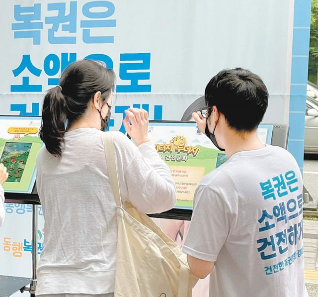 서울 마포구의 한 복권판매점 앞에서 복권판매인과 시민들이 복권 건전문화 캠페인에 참여하고 있다.