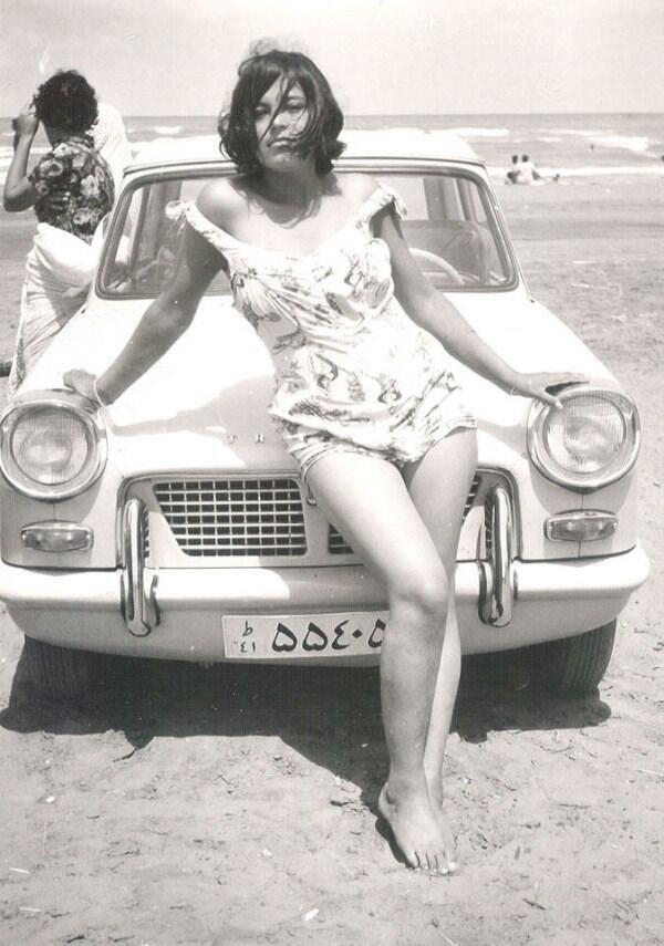 1960년대 이란 바닷가에서 수영복을 입은 여인이 차량 보닛에 기대 포즈를 취하고 있다.