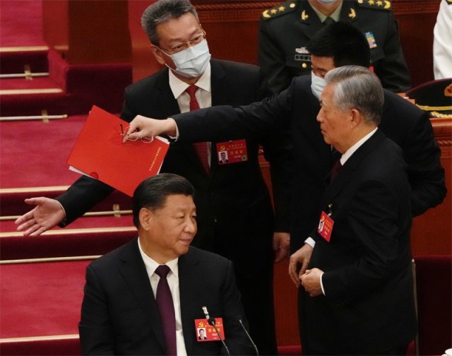 22일 중국 베이징 인민대회당에서 열린 중국 공산당 전국대표대회 폐막식 도중 후진타오 전 주석(오른쪽)이 수행원으로 보이는 남성에게 팔을 잡힌 채 나가고 있다. 베이징=AP/뉴시스