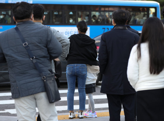 반짝 추위가 찾아온 24일 오전 서울 광화문네거리에서 한 어린이가 엄마 품에 안겨 건널목 신호를 기다리고 있다. 기상청은 내일 서울 최저기온이 5도까지 떨어지며 추위가 이어지다가 오는 26일 낮부터 풀릴 것으로 예보했다. 2022.10.24 뉴스1