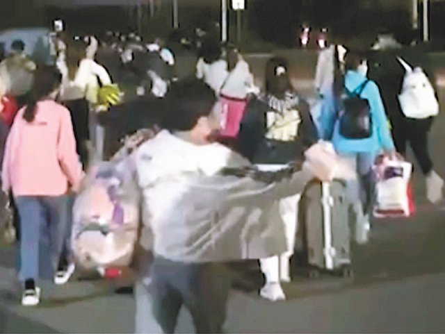 지난달 29일 중국 허난성 정저우의 대만 폭스콘(훙하이정밀공업) 공장 근로자들이 여행가방 등을 든 채 서둘러 공장을 빠져나가고 있다. 정저우=AP 뉴시스