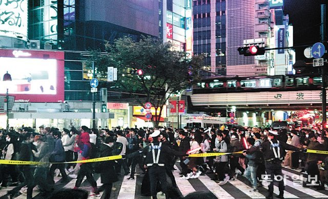 지난달 31일 일본 도쿄 시부야 스크램블 교차로에서 경찰들이 로프를 이어 잡고 보행자를 통제하고 있다. 도쿄=이상훈 특파원 sanghun@donga.com