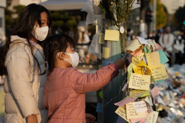 8일 오후 서울 용산구 이태원역 1번 출구에 마련된 이태원 참사 희생자 추모공간에서 한 어린이가 작성한 추모 글귀를 붙이고 있다. 뉴스1