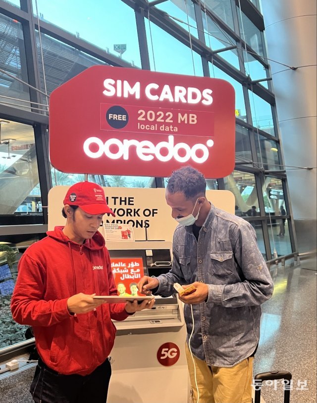 카타르 도하 하마드 국제공항 출구에서 무료 유심칩을 나눠주고 있는 이동통신사 스태프(왼쪽)와 수령 서명을 하는 공항이용객. 도하=송은석 기자 silverstone@donga.com