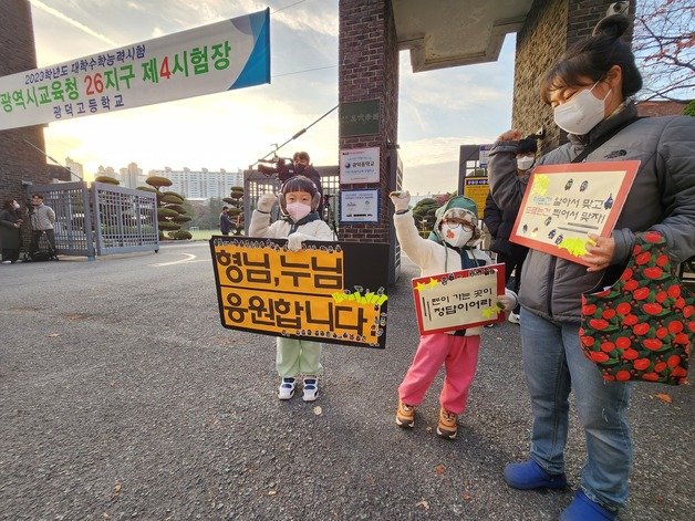 17일 오전 2023학년도 대학수학능력시험이 치러지는 광주 서구 광덕고 앞에서 화정동에 사는 최설·최율 형제가 엄마와 함께 수능 응원 피켓을 들고 응원하고 있다./뉴스1