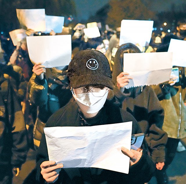 27일(현지 시간) 베이징에서 중국의 신종 코로나바이러스 감염증 봉쇄 정책인 ‘제로 코로나’에 항의하는 시위에 나선 시민들이 아무것도 쓰여 있지 않은 A4용지 백지를 들고 있다. 베이징=AP 뉴시스