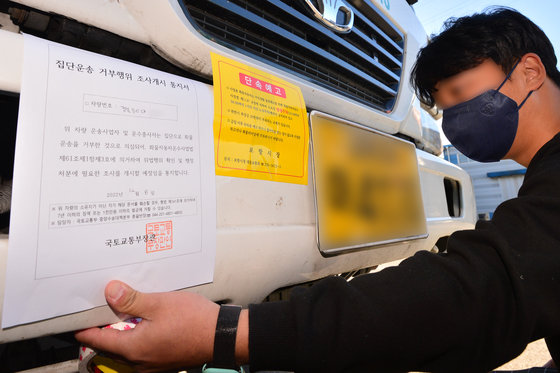 8일 오후 정부가 화물연대 파업과 관련 시멘트에 이어 철강과 정유부문에 업무개시명령을 발동했다. 국토부 관계자가 경북 포항시 남구 철강공단에 멈춰서 있는 화물연대 포항지부 소속 화물차량에 업무개시명령서(집단운송 거부행위 조사개시 통지서)를 부착하고 있다. 2022.12.8 뉴스1