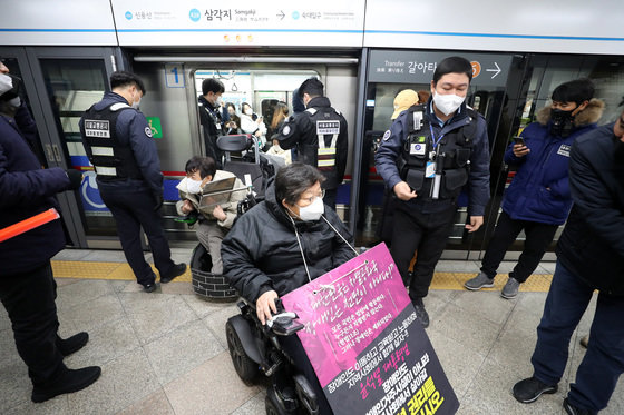 전국장애인차별철폐연대 회원들이 지난 7일 서울 용산구 삼각지역에서 장애인 권리 예산 확보를 위한 지하철 타기 선전전을 위해 치하철에 탑승 후 하차하고 있다. 2022.12.7 뉴스1