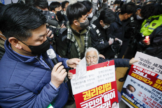 삼각지역장이 13일 오전 서울 용산구 삼각지역에서 장애인 권리 예산 확보를 위한 지하철 타기 선전전하는 전국장애인차별철폐연대 회원들에게 안내 방송하고 있다. 서울교통공사는 이날부터 전장연의 지하철 운행방해 행위로 인해 열차 지연이 발생시 역을 무정차 통과한다고 밝혔으나, 삼각지역을 무정차 통과한 열차는 없었다. 2022.12.13/뉴스1