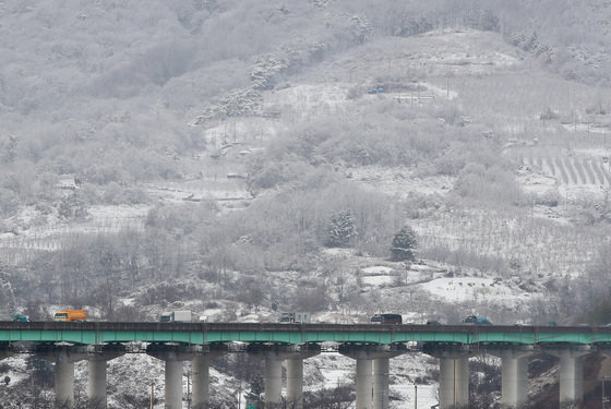 경북 문경과 북동 산지에 대설주의보가 발효된 13일 오후 문경읍 백화산 자락에 흰 눈에 뒤덮여 인근 중부내륙고속도로를 지나는 차량이 거북이운행을 하고 있다. 2022.12.13 뉴스1