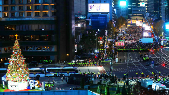 지난 11월19일 오후 서울 중구 서울광장에 설치된 크리스마스 트리가 점등식에 맞춰 환하게 불을 밝히고 있다. 트리 우측 숭례문 앞에서는 촛불행동 관계자들이 대규모 집회를 하고 있다. 2022.11.19/뉴스1