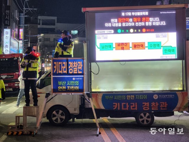 17일 오후 부산 광안리해수욕장에서 열린 부산 불꽃축제에 많은 인파가 집결하자 지상 70㎝ 높이의 사다리에 오른 ‘키다리 경찰관’이 이동 방향을 안내하고 있다. 부산=김화영 기자 run@donga.com