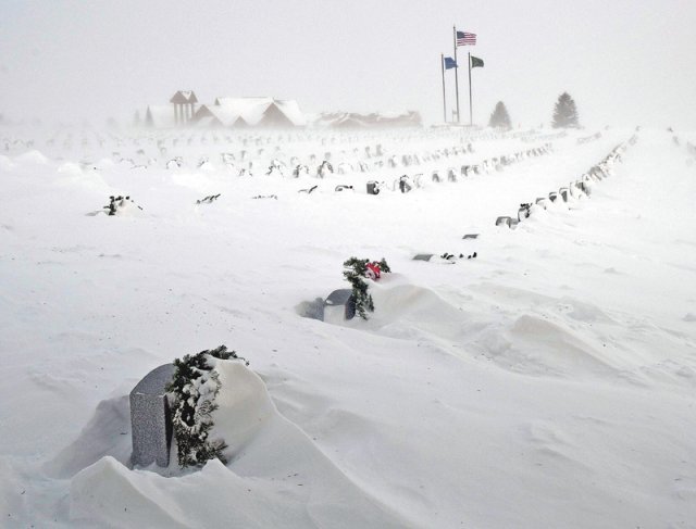 폭설에 뒤덮인 美 참전용사 묘지 22일(현지 시간) 미국 북서부 노스다코타주 맨던에 있는 참전용사 묘지가 폭설에 뒤덮였다. 쌓인 눈 속에 일부 묘비와 조화가 보이고 멀리 성조기가 나부끼고 있다. 맨던=AP 뉴시스