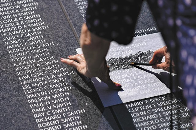지난해 7월 제막식이 거행된 미국 워싱턴 한국전 참전용사 기념공원 내 추모의 벽. 한 방문객이 대리석에 새겨진 전사자의 이름 위에 종이를 대고 탁본을 뜨고 있다. 워싱턴=AP 뉴시스