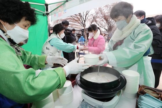 설 명절을 맞은 22일 서울 종로구 운현궁에서 열린 ‘떡국 나눔 마당’에서 자원봉사자들이 시민들에게 떡국을 나눠주고 있다. 2023.1.22 뉴스1