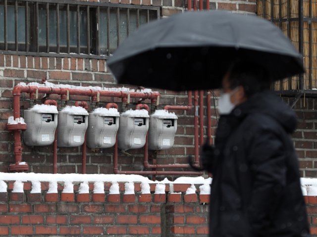 26일 서울 시내 주택가 벽면에 설치된 가스계량기 앞을 한 시민이 우산을 쓴 채 지나가고 있다. 주택용 도시가스 요금은 2022년 1년 동안 38.5% 올랐다. 뉴스1