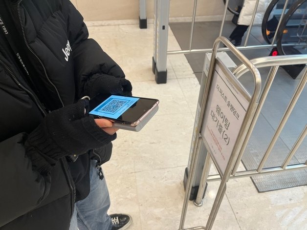 더 현대 서울 관계자가 입구 앞에서 큐알코드 안내를 하고 있다. 뉴스1