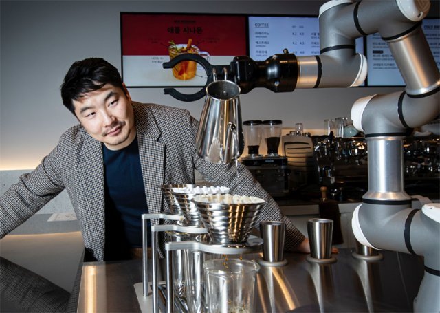 황성재 엑스와이지 대표이사가 세계에서 처음으로 선보인 드립 커피 서비스 로봇의 커피 제조 과정을 지켜보고 있다. 물의 온도, 물을
 붓는 방식 등에 따라 커피의 맛을 달리하는 6가지 방식이 있다. 제조 방식은 클라우드에서 각 매장의 로봇으로 온라인으로 
전달된다. 새로운 메뉴를 추가하기 용이하다. 엑스와이지 제공