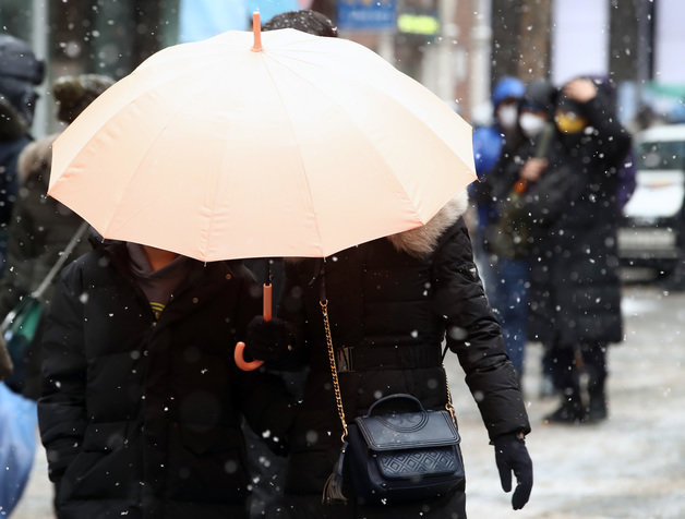 전국 곳곳에 눈이 내린 26일 오후 서울 중구 명동거리에서 우산을 쓴 시민들이 발걸음을 옮기고 있다. 2023.1.26. 뉴스1