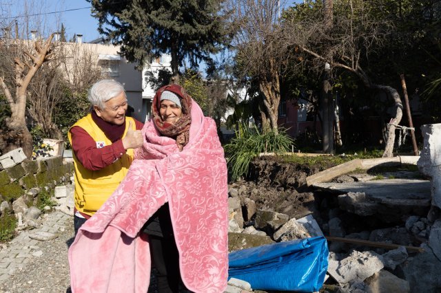봉사단이 전해준 담요를 몸에 감싼 한 노인이 밝은 웃음을 보이고 있다. 한국기독교연합봉사단 제공