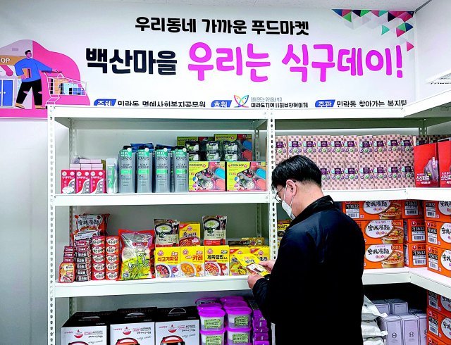 부산 수영구 민락동 행정복지센터는 취약계층 주민이 민원실의 진열대에 놓인 생필품을 가져다 쓸 수 있게 하는 ‘우리는 식구데이’ 사업을 추진하고 있다. 민락동 관계자가 이 진열대의 생필품들을 정리하고 있다. 부산 수영구 제공