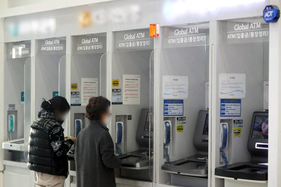 서울 시내 한 건물에 설치된 은행의 현금인출기(ATM)에서 시민들이 입출금을 하는 모습. 2022.12.27. 뉴스1