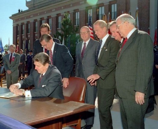 1988년 10월 25일, 로널드 레이건 당시 미국 대통령이 프랭크 칼루치 미 국방장관 등이 지켜보는 가운데 제대군인부(한국의 보훈부) 승격 법안에 서명하고 있다. 미 제대군인부 홈페이지
