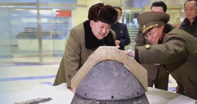 김정은 북한 국무위원장이 2016년 3월 15일 대기권 재진입 고열 실험을 견뎌낸 미사일 탄두 부분을 살펴보며 웃고 있다. 동아DB
