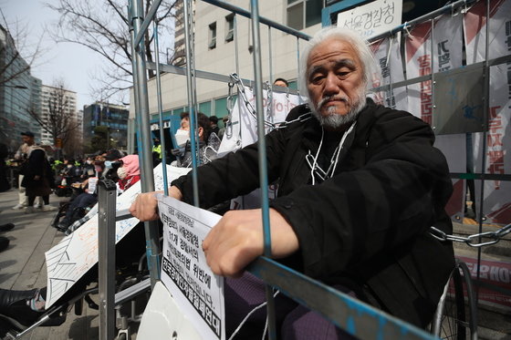 박경석 전국장애인차별철폐연대(전장연) 대표가 17일 오전 서울 종로구 서울지방경찰청 앞에서 법원의 체포영장 발부에 따른 입장발표 기자회견에 참석해 철창과 쇠사슬로 이동의 자유 제한을 표현하고 있다. 2023.3.17 뉴스1