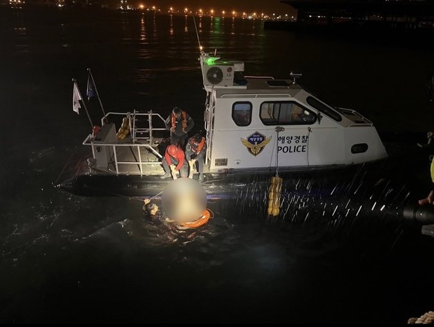 23일 오전 3시58분께 부산 감천항 인근 해상에 빠진 차량에서 자력으로 빠져나온 30대 여성을 해경이 구조하고 있다.(부산해경 제공)