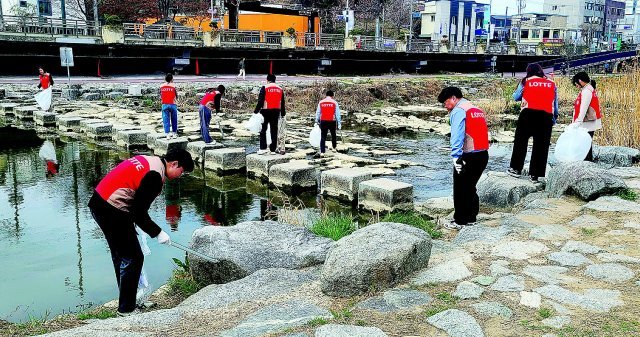 롯데백화점 광주점 임직원들이 22일 광주천변에서 환경 정화 활동을 벌이고 있다. 롯데백화점 광주점 제공