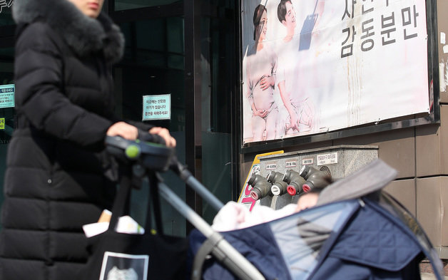 23일 오후 서울 시내의 한 산부인과 앞을 시민이 유모차에 유아를 태우고 지나는 지나고 있다. 2023.2.23/뉴스1