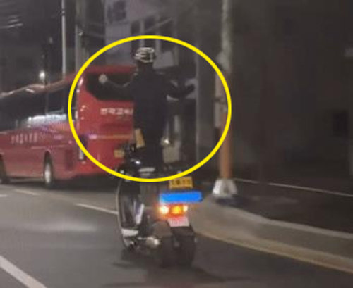 지난 21일 오후 대전시 동구 용운동에서 50대 배달업자 A 씨가 오토바이 주행 중 조종 손잡이를 놓은 채 안장에 올라가 두 팔을 앞뒤로 흔들고 있다. 온라인 커뮤니티
