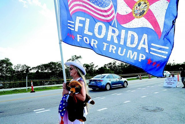 2일(현지 시간) 미국 플로리다주 팜비치에 있는 도널드 트럼프 전 대통령의 마러라고 자택 근처에서 한 여성이 ‘플로리다는 트럼프를 지지한다’고 쓴 깃발을 들고 있다. 팜비치=AP 뉴시스