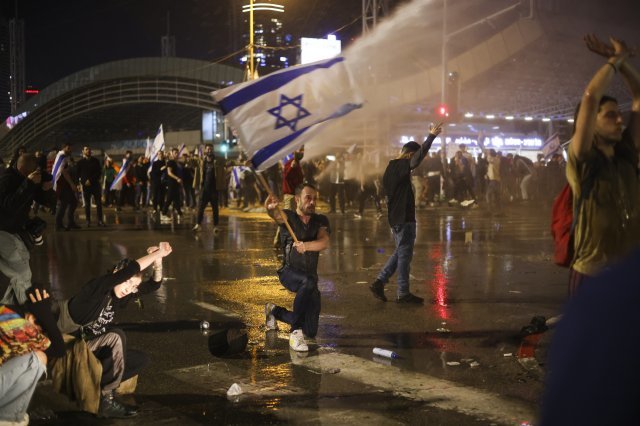 지난달 27일 이스라엘 텔아비브에서 열린 ‘사법부 무력화’ 법안 반대 시위에 나온 시민이 경찰의 물대포를 맞으며 이스라엘 국기를 흔들고 있다. 텔아비브=AP 뉴시스