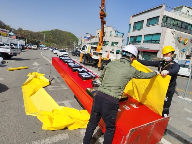 12일 오전 9시45분께 예산시장 내에 세워졌던 ‘백종원 거리’ 간판이 철거돼 차량에 옮겨 싣기 위해 천으로 감싸고  있다. 2023.04.12