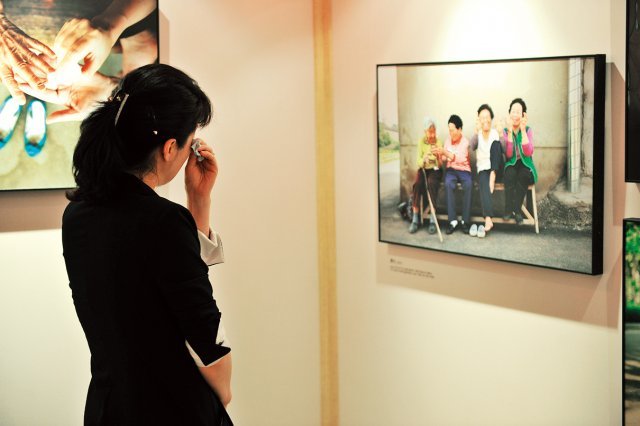 ‘우리 어머니’ 글과 사진展의 작품을 보며 눈물을 닦고 있는 관람객.