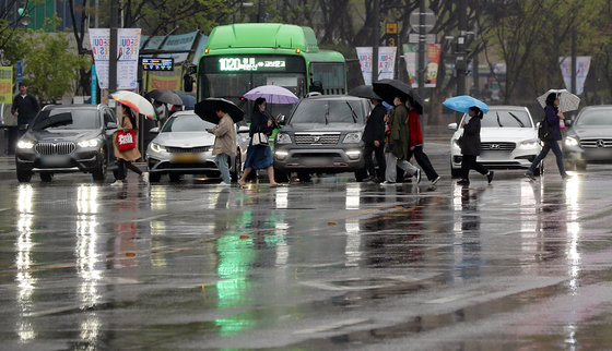 서울 등 수도권 일대에 비가 내린 11일 서울 종로구 광화문광장 인근에서 우산을 쓴 시민들이 길을 건너고 있다. 2023.4.11 뉴스1