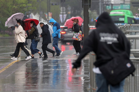 서울 등 수도권 일대에 비가 내린 11일 서울 종로구 광화문광장 인근에서 우산을 쓴 시민들이 길을 건너고 있다. 2023.4.11. 뉴스1