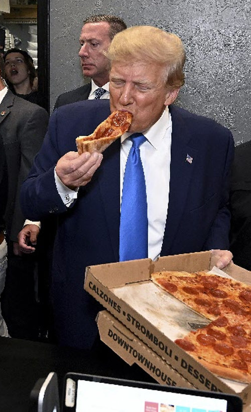 도널드 트럼프 전 미국 대통령이 21일 플로리다주 포트마이어스에서 공화당원 모금 행사를 마친 뒤 인근 식당에 들러 피자를 먹고 있다. 포트마이어스=AP 뉴시스