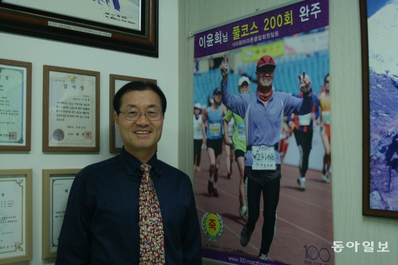 이윤희 대표가 사무실에서 마라톤 풀코스 200회 완주 사진 앞에서 포즈를 취했다. 동아일보 DB