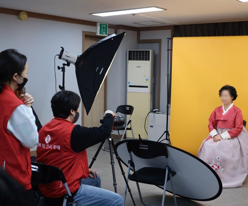 롯데정보통신 직원들이 ‘행복사진 봉사활동’에 참여해 한 어르신을 촬영하고 있다. 금천구 제공