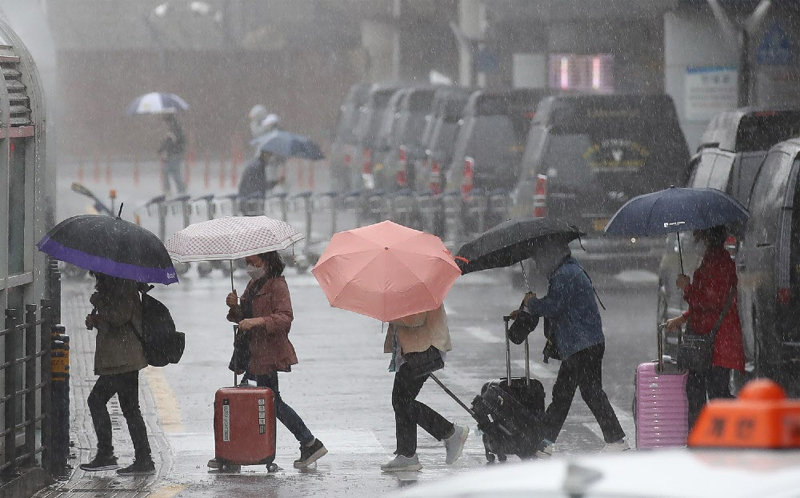 4일 제주국제공항 1층 도착장에 우산을 쓴 관광객들이 쏟아지는 장대비 속에서 발걸음을 재촉하고 있다. 어린이날(5일)을 거쳐 6일까지 제주를 포함한 전국에 최대 400mm의 폭우가 내릴 것이라고 기상청은 예보했다. 제주= 뉴시스