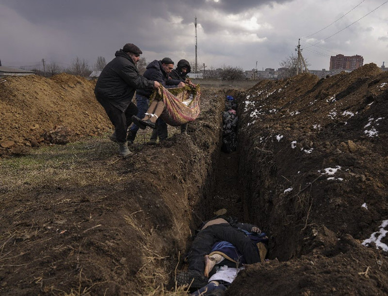 지난해 3월 9일 우크라이나 마리우폴 외곽 지역에서 주
민들이 시신을 제대로 수습도 못 하고 참호처럼 판 고
랑에 내려놓고 있다. AP통신 사진기자팀의 퓰리처상
‘속보 사진 부문’ 수상작. 마리우폴=AP 뉴시스