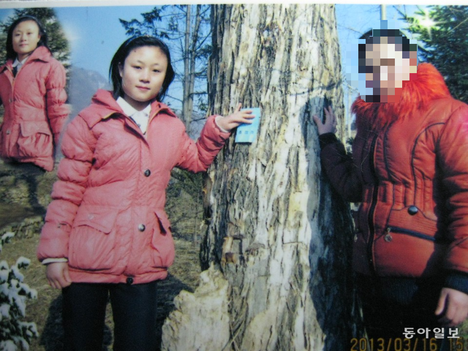 북한 김정숙군 제1중학교 졸업식 전날 친구와 함께 사진을 찍은 전주옥 씨(왼쪽). 이 학교에는 구내의 오래된 나무 앞에서 졸업 사진을 찍는 전통이 있다. 이틀 뒤 전 씨는 압록강을 넘었다.