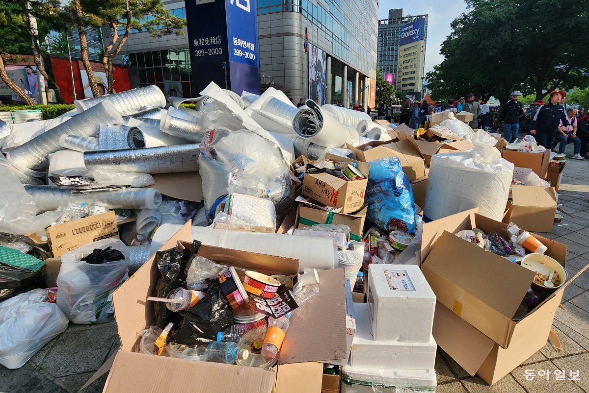 서울 종로구 청계광장 일대를 점거하고 1박 2일 노숙 집회를 진행한 전국민주노동조합총연맹(민노총) 건설노조 조합원들이 16일 밤 
광장을 차지한 채 술판을 벌이고 있다(위쪽 사진). 조합원들이 노숙 집회를 하며 남긴 쓰레기들이 다음 날인 17일 오전 서울 
종로구 동화면세점 앞에 쌓여 있다. 장승윤 tomato99@donga.com·박영대 기자