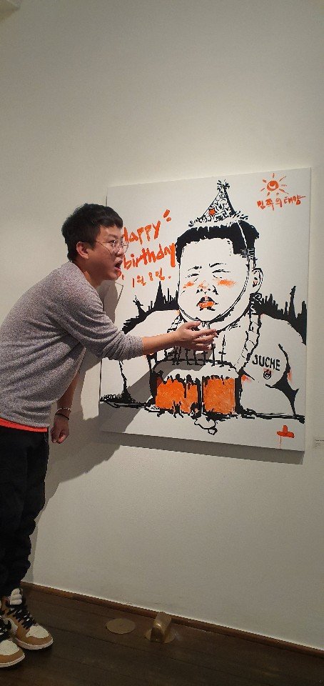 2020년 1월 8일 김정은 생일에 열린 한 전시회에서 강 씨가 김정은을 풍자한 그림을 설명하고 있다.