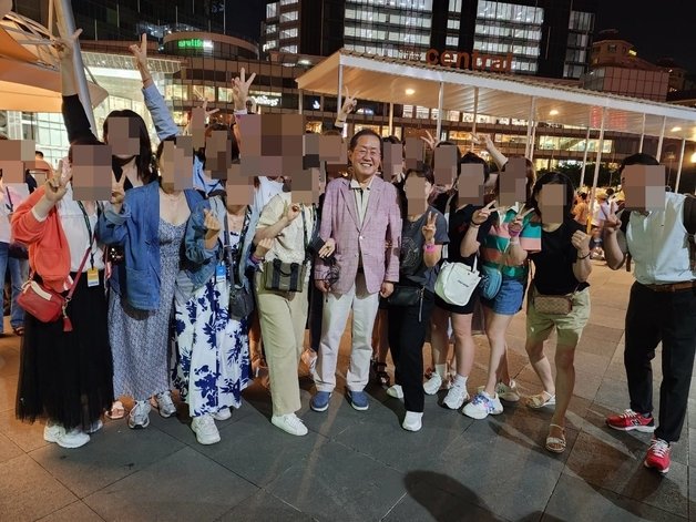 대구 50년 밑그림을 그리기 위해 해외출장 중인 홍준표 대구시장이 지난 21일 밤 싱가포르 마리나베이를 찾았다가 만난 한국 관광객들 기념촬영 요구에 응하고 있다. (SNS 갈무리)