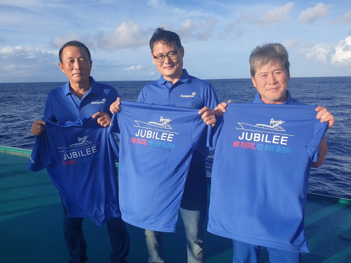 남태평양에서 조업 중인 동원산업 선원들이 ‘플라스틱 저감화 3개년 계획’의 슬로건이 적힌 티셔츠를 들고 있다. 동원산업 제공